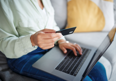 UK dating app subscription rules illustrated by a woman holding a payment card while using a laptop