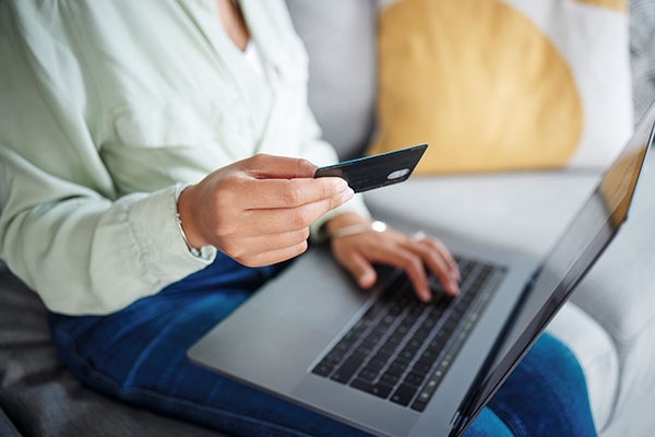 UK dating app subscription rules illustrated by a woman holding a payment card while using a laptop