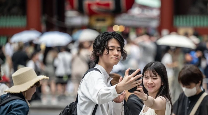 Two young adults taking a selfie outside a temple in Tokyo.